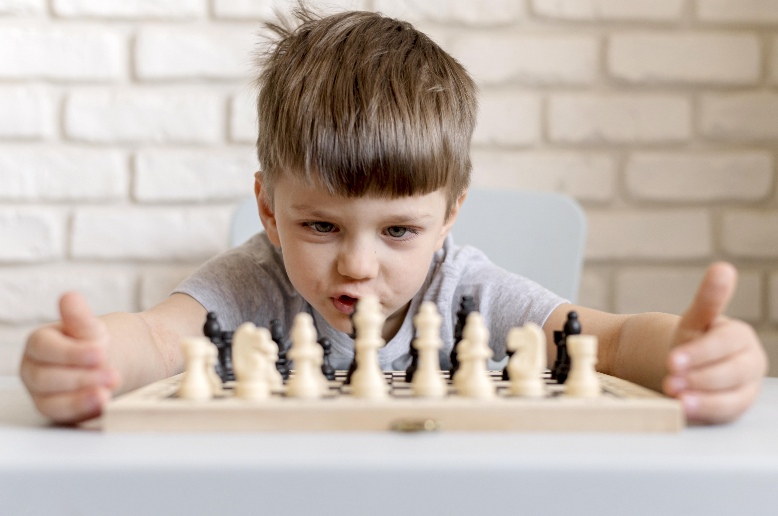chłopiec patrzy na rozłożone szachy