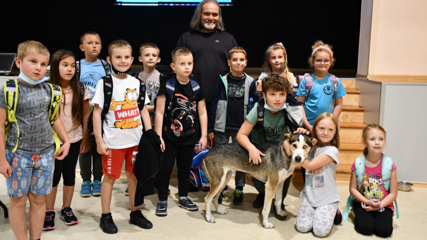 grupa dzieci z prowadzącym spotkanie i jego psem