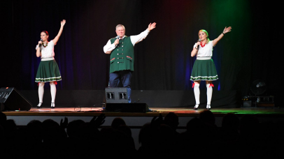 trójka wokalistów na scenie z rękoma podniesionymi do góry